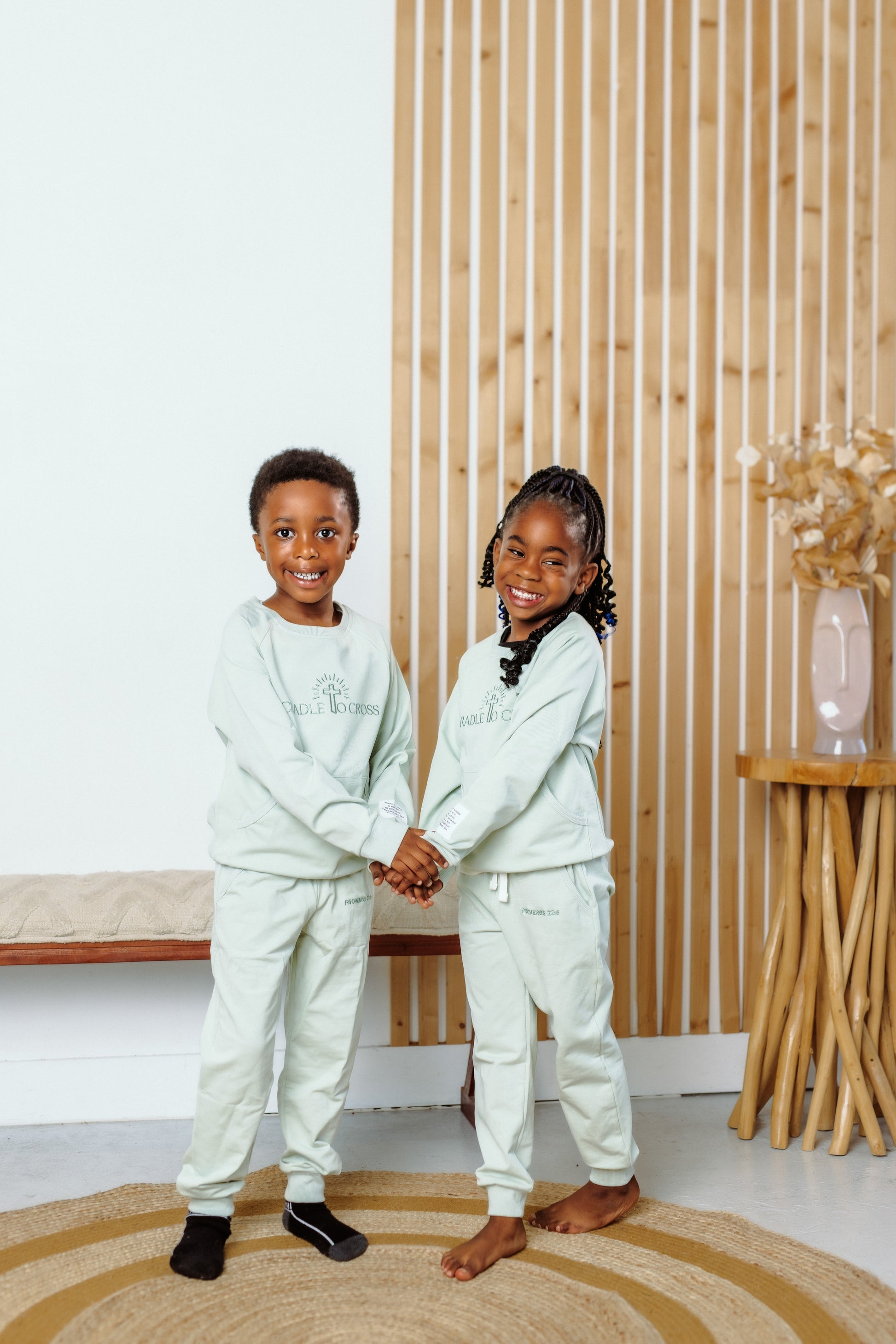 Two children wearing matching outfits standing in a room with wooden paneling.