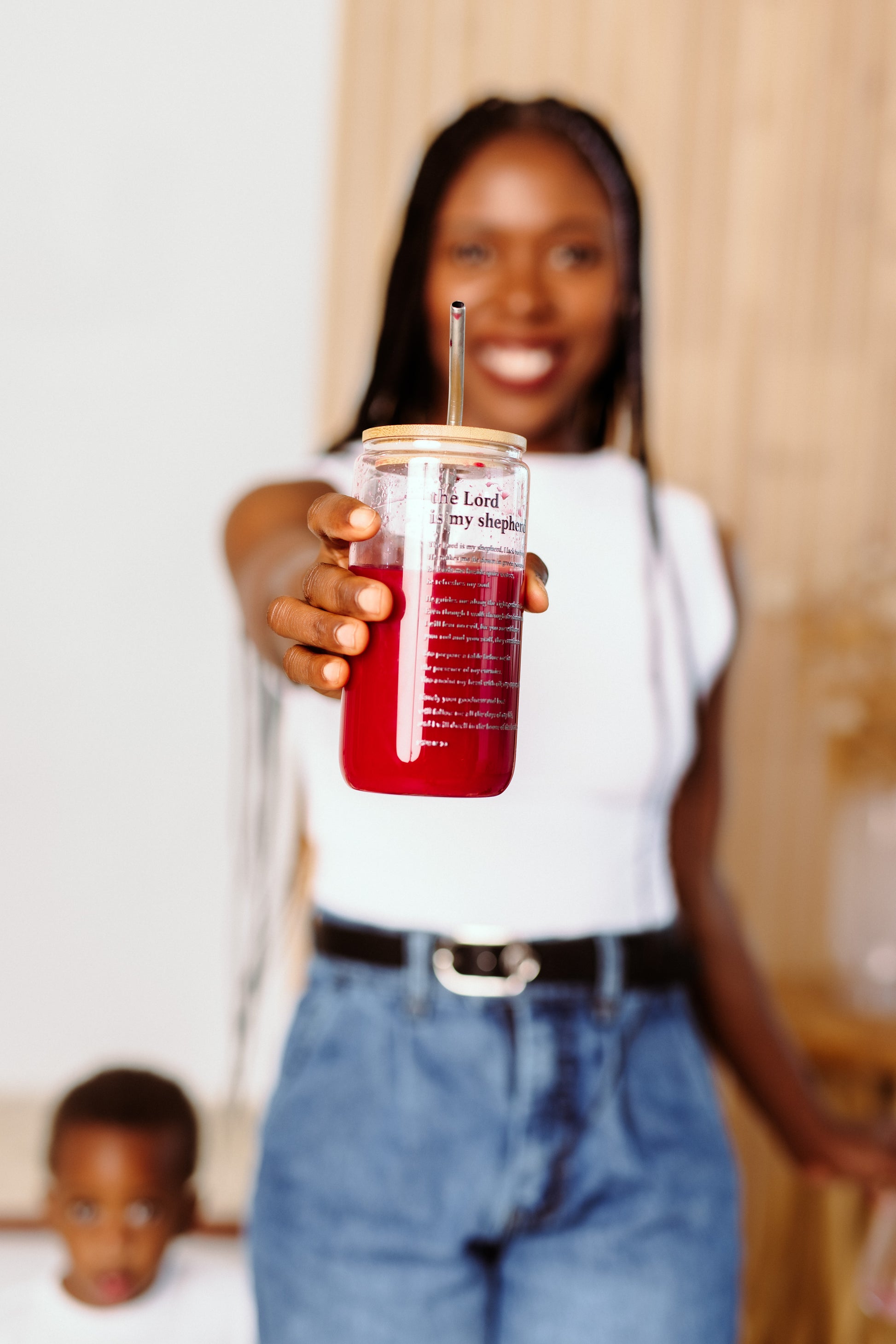 Woman holding a  tumbler with a straw, blurred background. The lord is my Shepheard on it. 